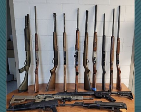 Una variedad de armas apoyadas contra una pared y sobre una mesa incautadas por oficiales de CBP en el puerto de entrada de Eagle Pass durante un examen de salida.