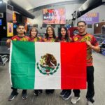 Atletas sosteniendo la bandera de México.