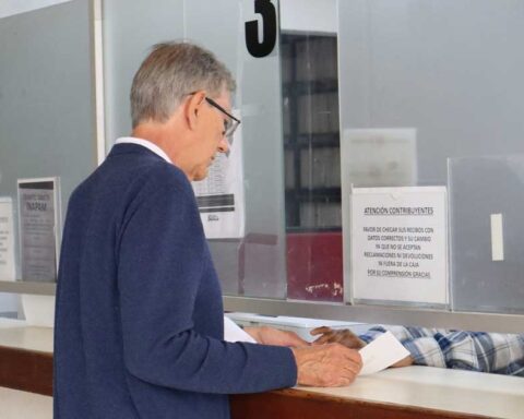 Adulto mayor pagando impuestos en ventanilla.